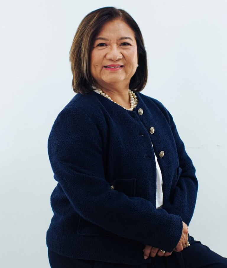 Studio portrait of a smiling female executive wearing a dark textured blazer or cardigan jacket.