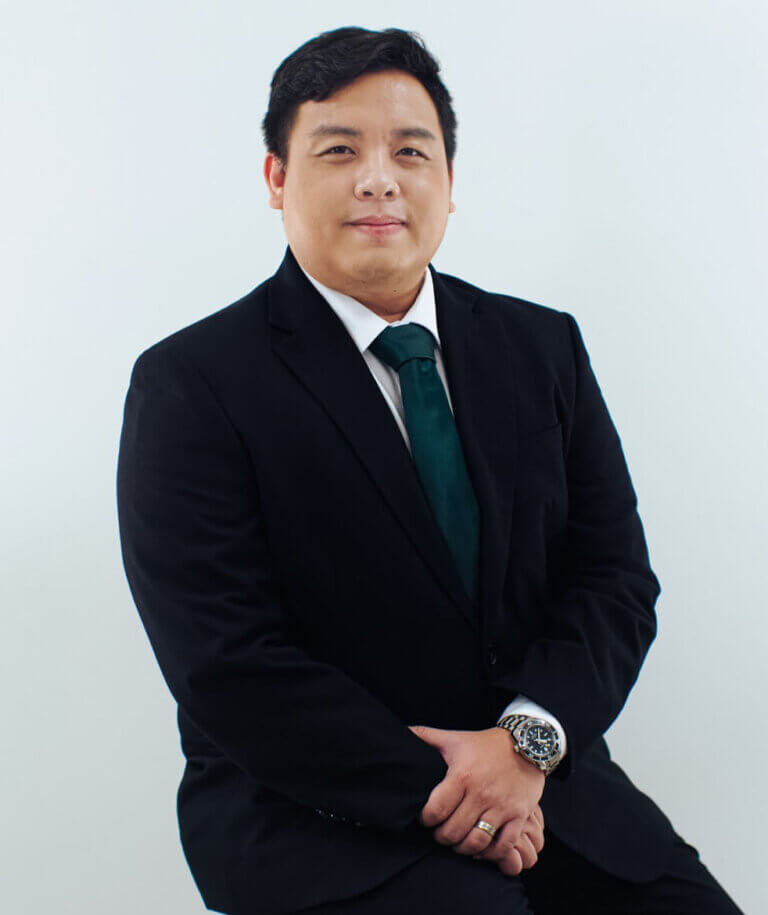 Professional studio headshot of a male executive wearing a dark business suit and a green necktie.