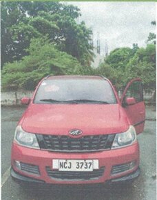 Bright red compact car parked outdoors with its passenger side door slightly ajar.