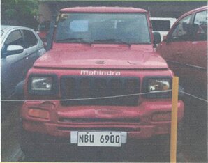 Frontal shot of a red Mahindra utility vehicle with its license plate clearly displayed on the bumper.